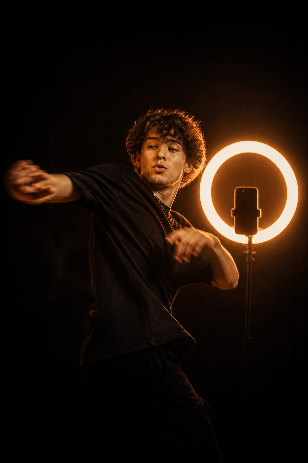 An energetic creator performing to a phone camera beside a ring light